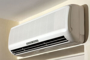 White ductless split air conditioning system mounted on interior wall with horizontal louvers and control panel visible.