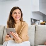 Happy,Mature,Older,Woman,Using,Digital,Tablet,Sitting,On,Couch