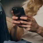 Close,Up,Smiling,Woman,Client,Browsing,Mobile,Phone,At,Home